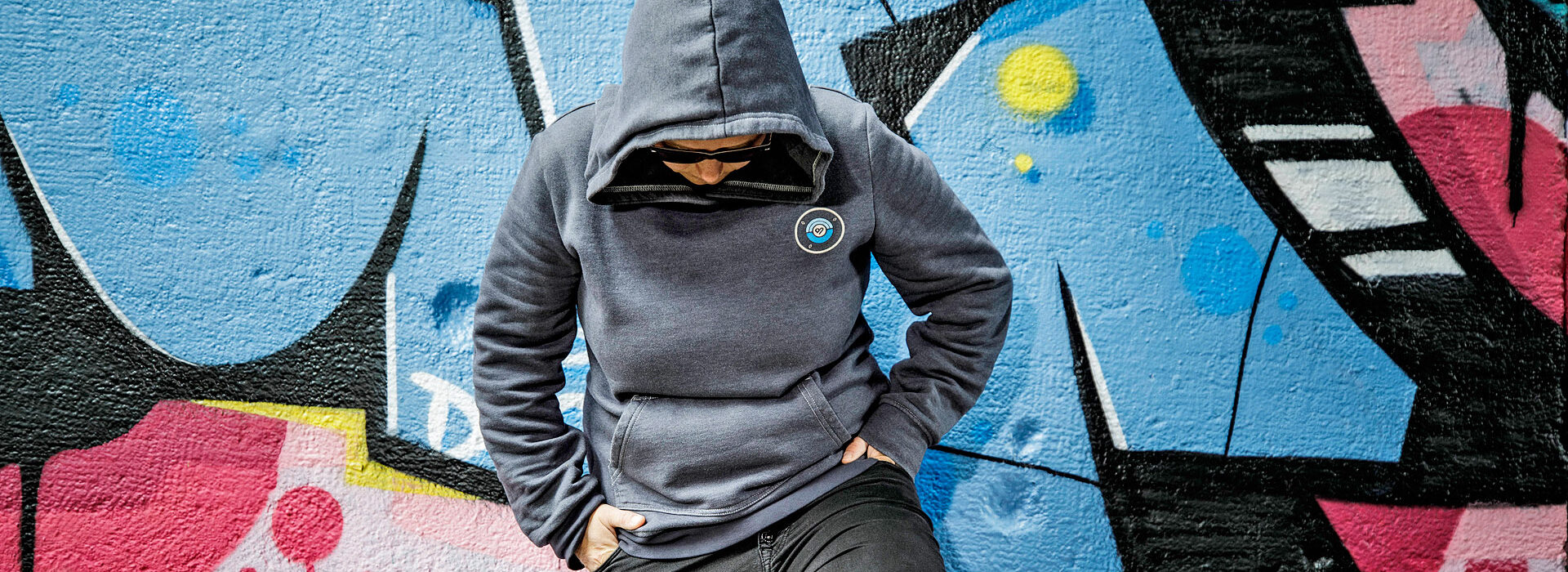 Foto: Jugendlicher mit Hoodie vor Grafittiwand