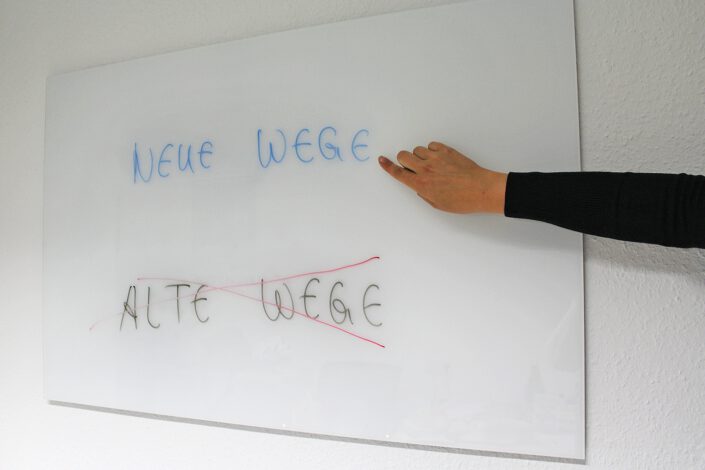 Foto: Whiteboard mit Text Neue Wege Alte Wege und einer richtungsweisenden Hand