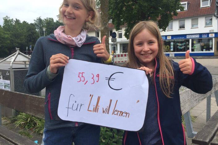 Foto: zwei Mädchen halten Schild mit Spendenerlös hoch